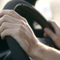 someone driving a car and holding the steering wheel someone driving a car and holding the steering wheel