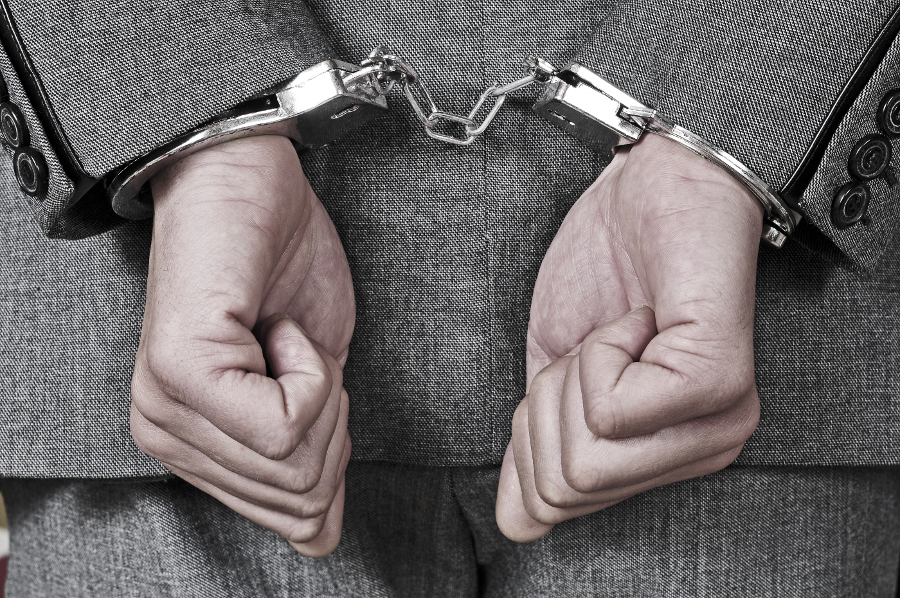 a man wearing a suit, with handcuffs in his wrists a man wearing a suit, with handcuffs in his wrists