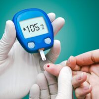 Doctor making blood sugar test. Hands with gloves on medical background